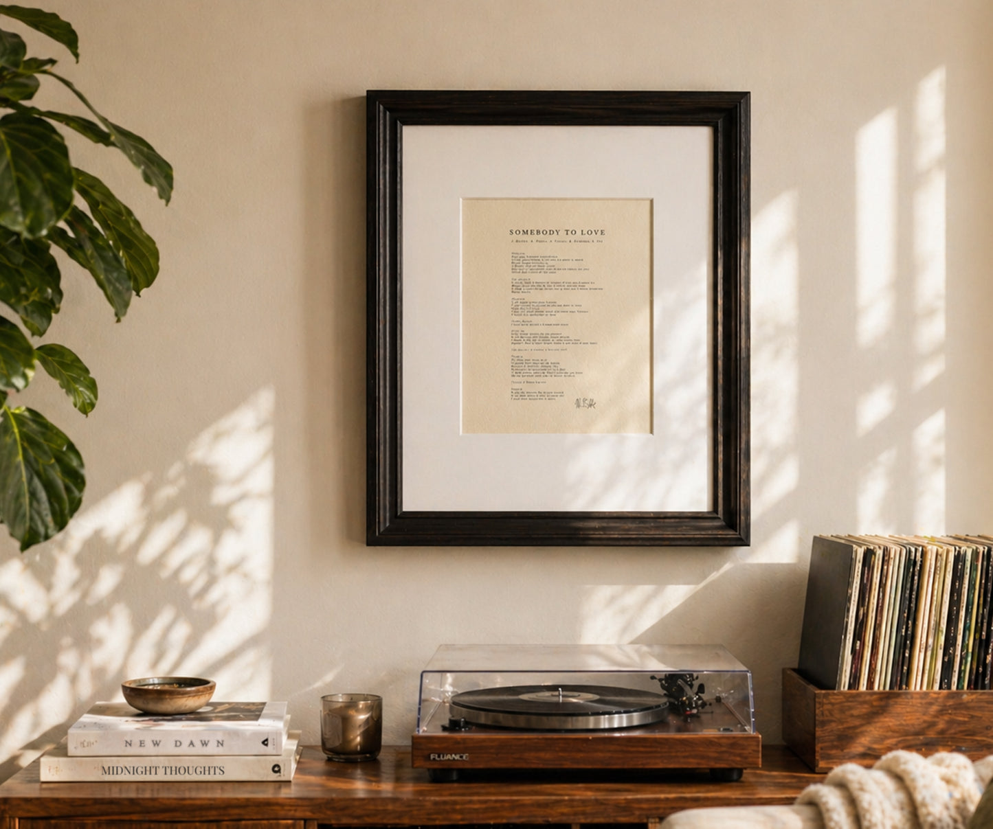 Framed artwork on a wall above a wooden console with a turntable and books.